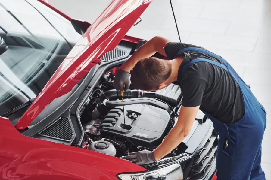 top-view-of-male-worker-in-uniform-that-repairs-red-automobile-1536x1024